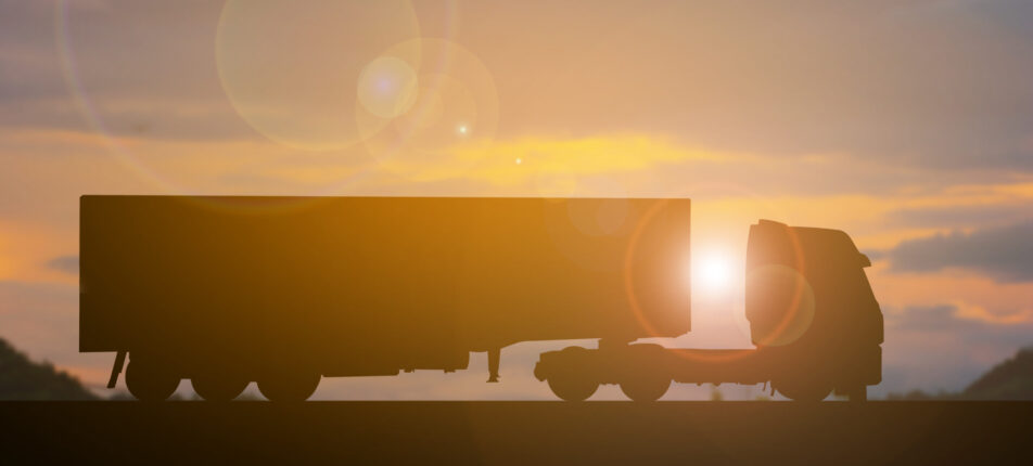 Silhouette cut out long truck on sunset background, long vehicle land transportation and shipping cargo concept, computer graphic flare light, copy space for individual text